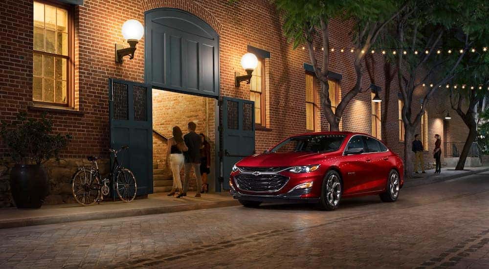 A red 2021 Chevy Malibu is shown from the front at an angle after leaving a dealer that has a Chevy Malibu for sale.