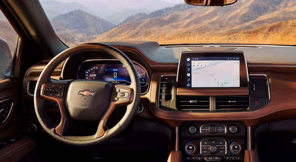 The tan interior of a 2023 Chevy Tahoe shows the steering wheel and infotainment screen.