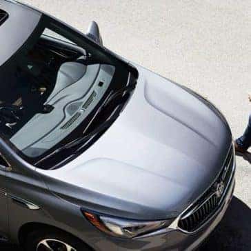 Skyview of a man in a plaid shirt walking toward his silver 2019 Buick Enclave
