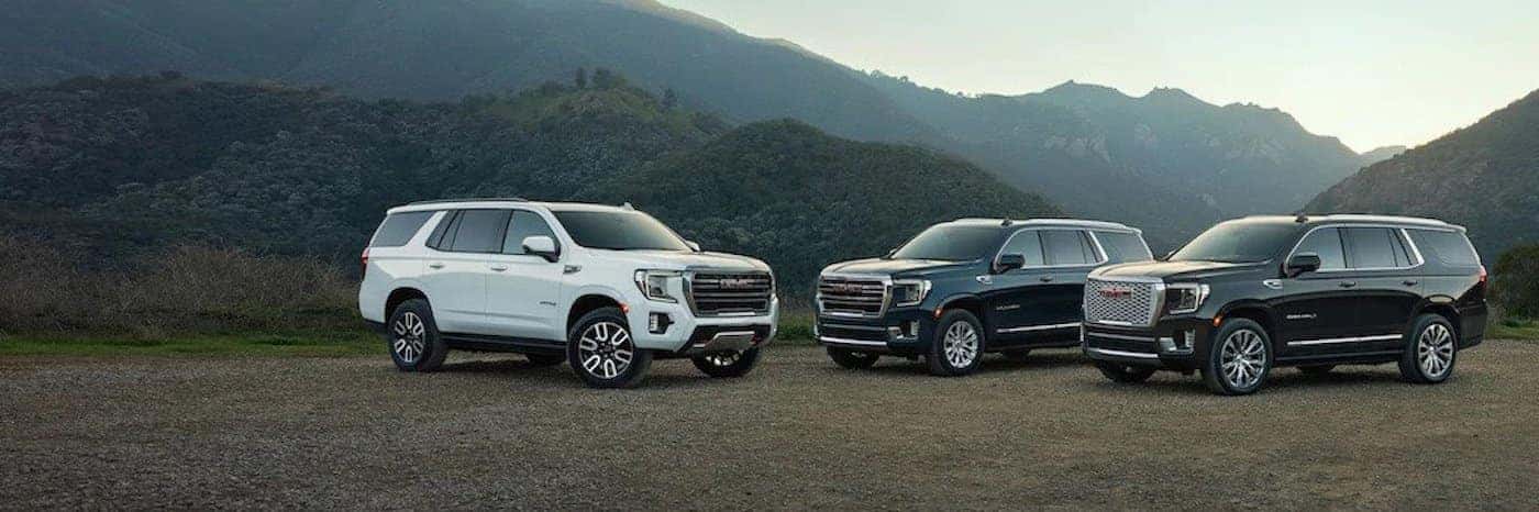 Three 2021 GMC Yukons parked in front of a mountain view