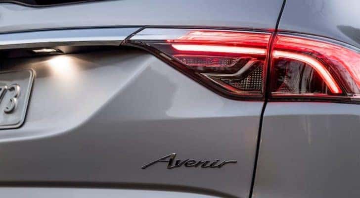 A close up shows the illuminated passenger taillight and badge on a silver 2022 Buick Enclave Avenir.