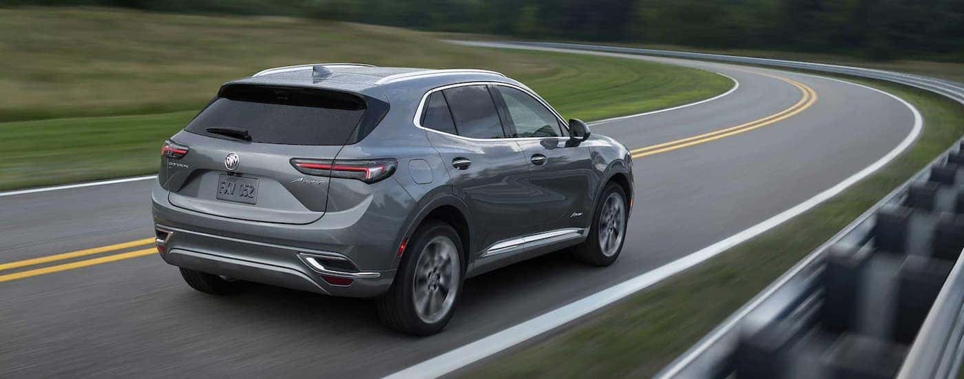 A dark grey 2022 Buick Envision Avenir is shown from behind rounding a corner.