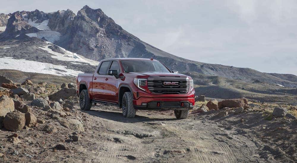 Front view of a red 2022 GMC Sierra 1500 AT4X driving down a mountainside dirt path