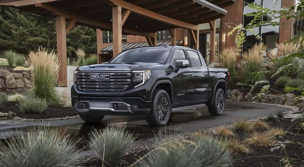 Black 2022 GMC Sierra Denali 1500 Ultimate parked under an outdoor garage after leaving a GMC dealer in Minot
