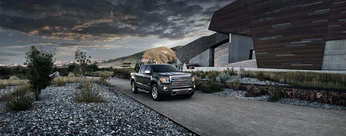 A black 2015 GMC Canyon Crew Cab SLT is shown parked outside of a modern building.