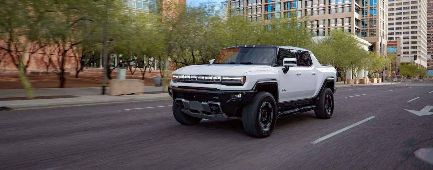 A white 2022 GMC Hummer EV is shown driving on a city street after leaving a GMC dealer in Minot.