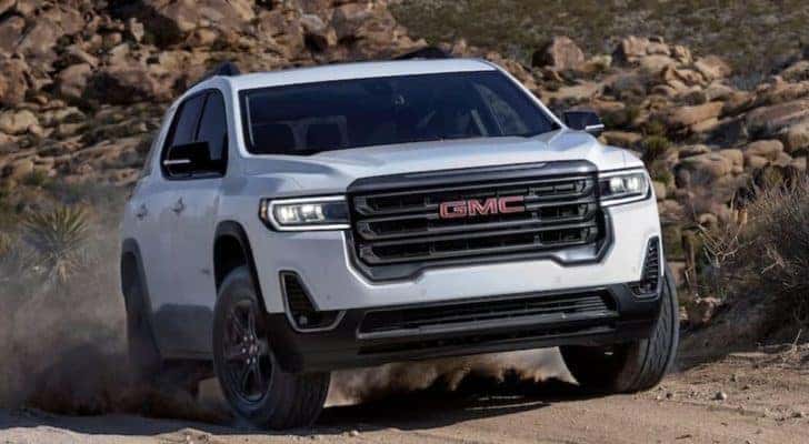 A white 2020 GMC Acadia is shown from the front driving on a dirt road.