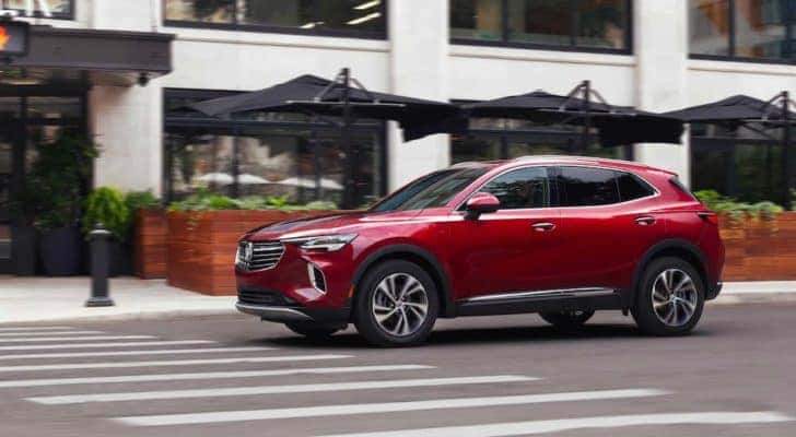 A red 2022 Buick Envision is shown driving in a city after visiting a Buick dealer.