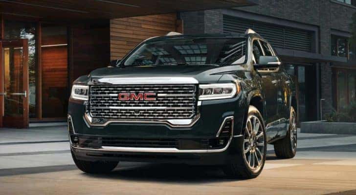 A black 2021 GMC Acadia is shown from the front parked in front of a building.