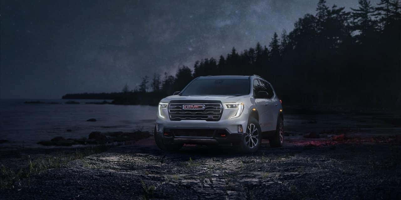 A white 2025 GMC Acadia parked at a lakebed at night