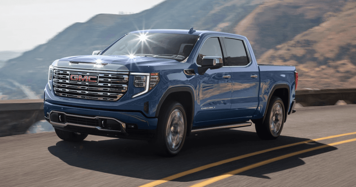 A blue 2025 GMC Sierra 1500 driving on a road on a cliffside