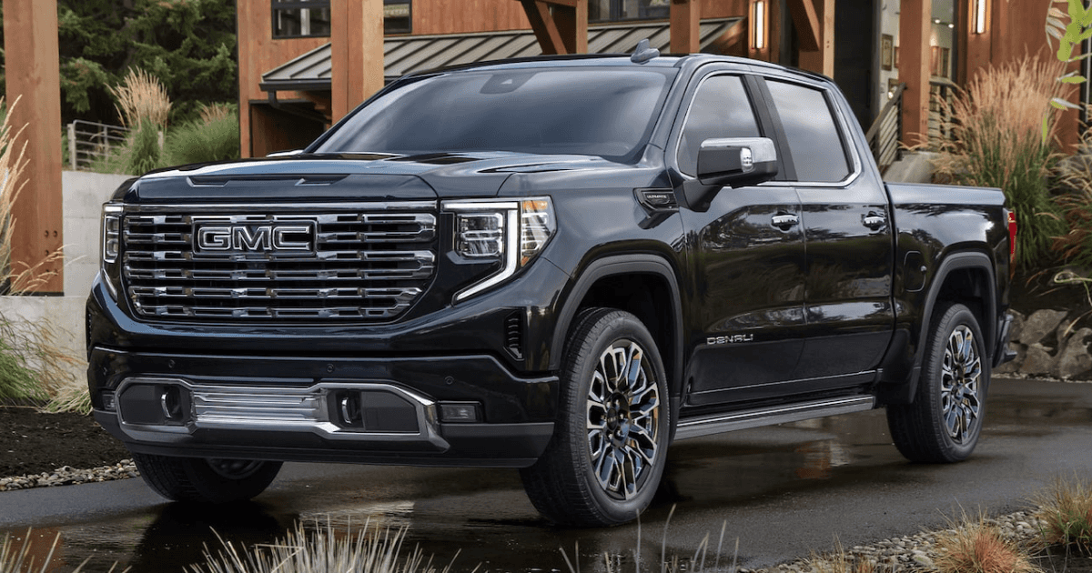A black GMC Sierra 1500 parked in the driveway of a nice house, surrounded by plants