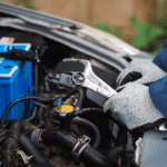 A close up of an engineer's hands, holding a wrench as they repair a vehicle's engine