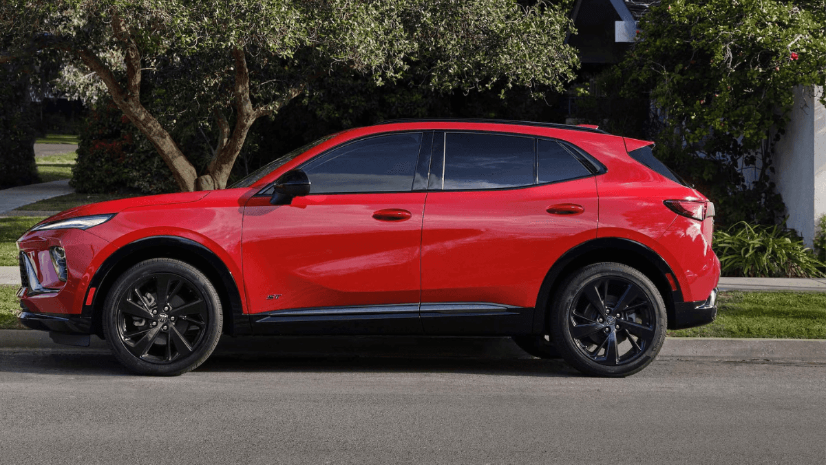 A red Buick Envision in profile, parked by a curb in a suburb