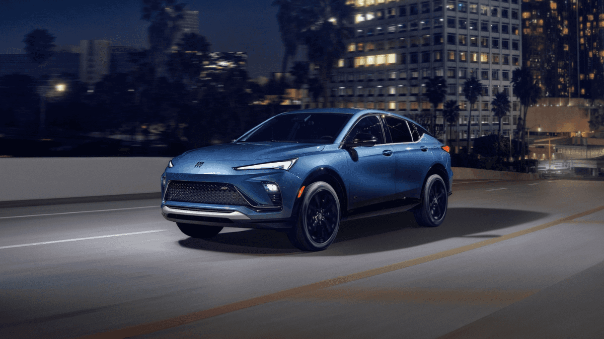 A blue Buick Envista driving down a road at night from a city