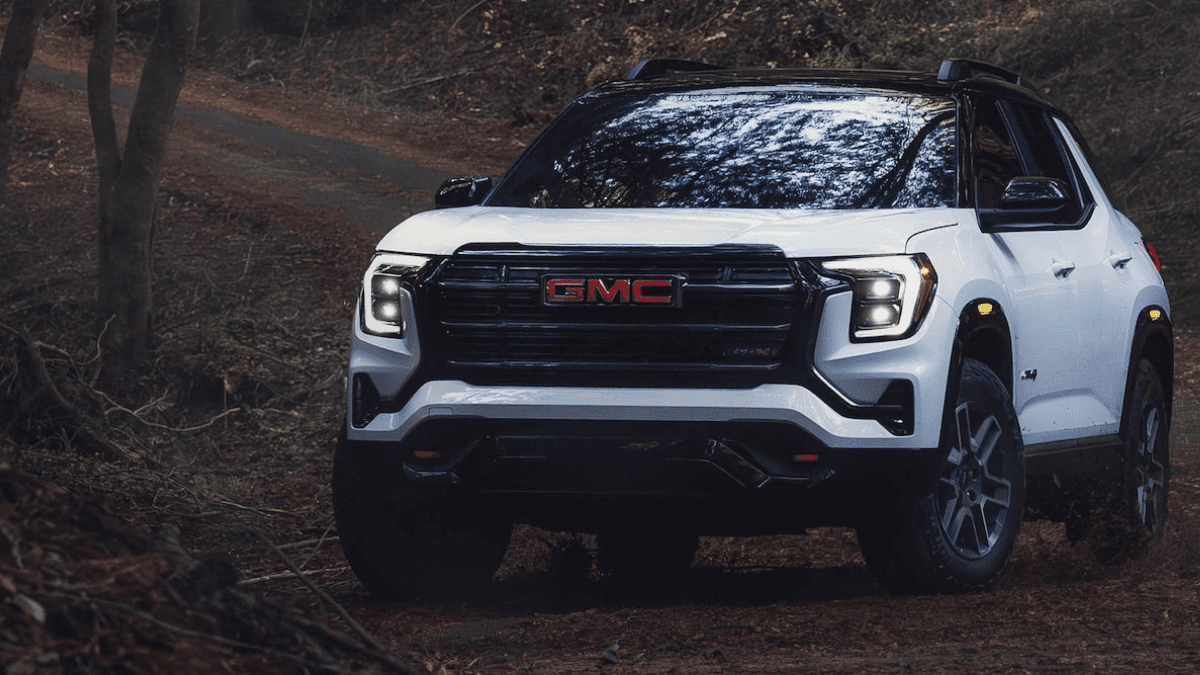 A white GMC Terrain driving off-road in a forest