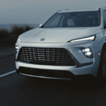 A white Buick Enclave driving on the road at dusk