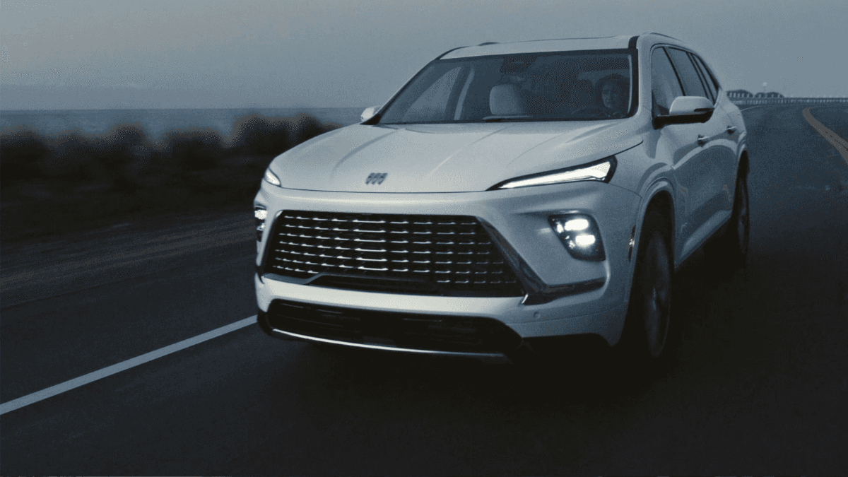 A white Buick Enclave driving on the road at dusk