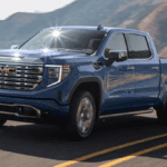 A blue GMC Sierra 1500 driving around a bend high on a hill