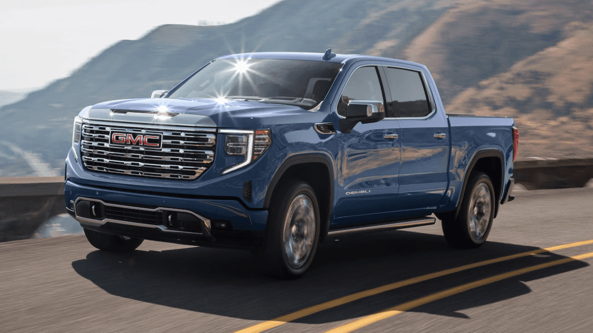 A blue GMC Sierra 1500 driving around a bend high on a hill