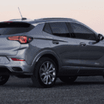 A light gray blue Buick Encore parked on a black sand beach