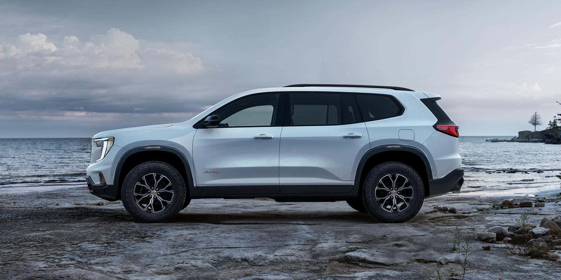 A white GMC Acadia parked at a beach
