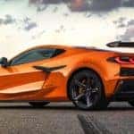 An orange 2023 Chevy Corvette Z06 is shown from the rear at an angle while parked after leaving a Chevy dealer.