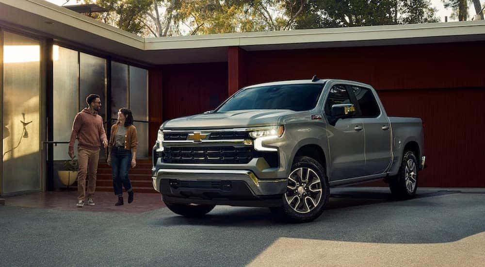 Couple walking toward their silver 2022 Chevy Silverado 1500 Z71 that is parked in a driveway