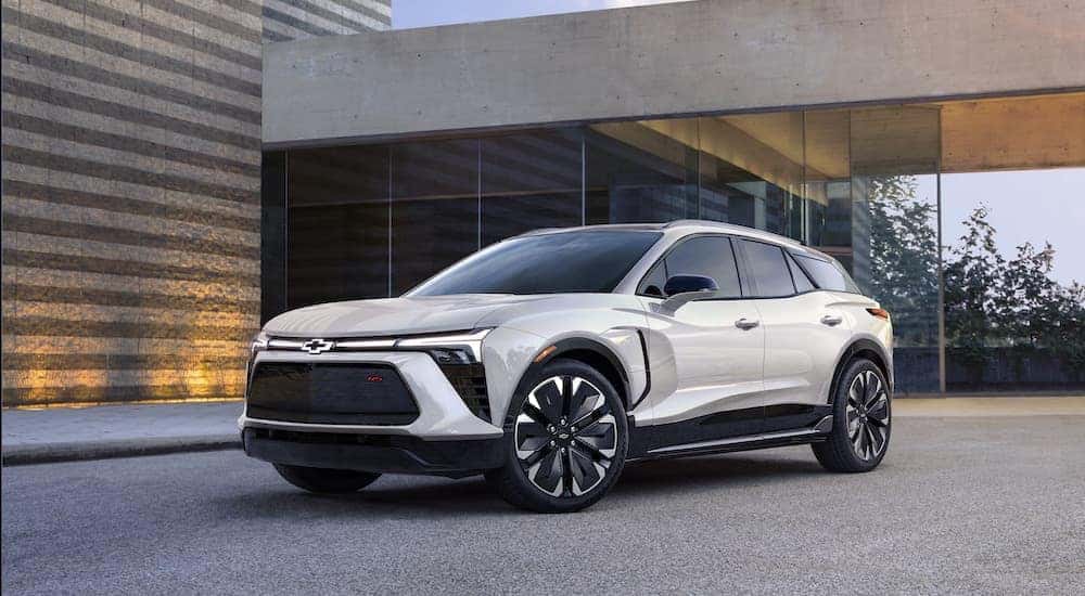 Front angled view of a white 2024 Chevy Blazer EV parked in the driveway of a modern home
