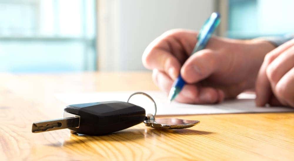 A customer is shown signing paperwork at a car dealership after deciding to sell their car.
