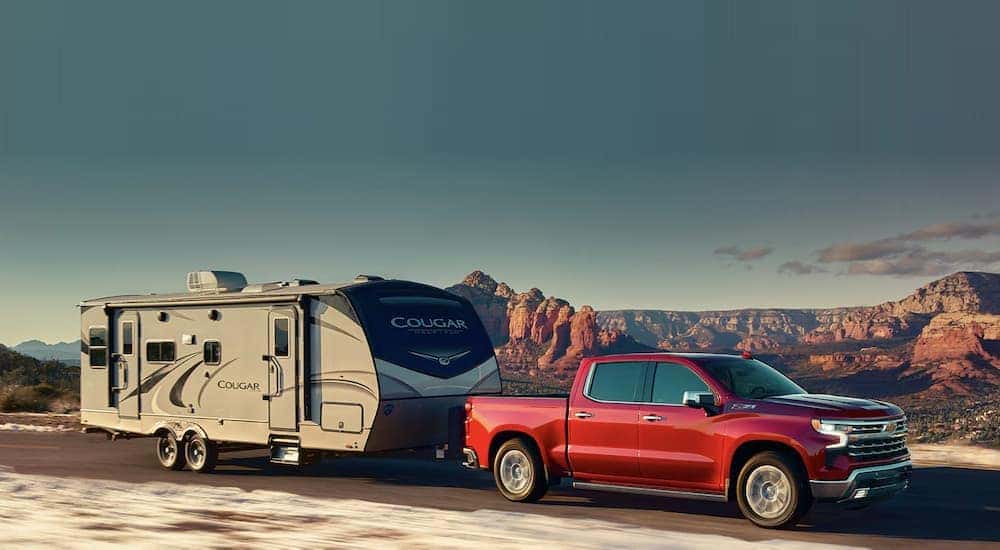 A red 2023 Chevy Silverado 1500 Z71 is shown towing a trailer.