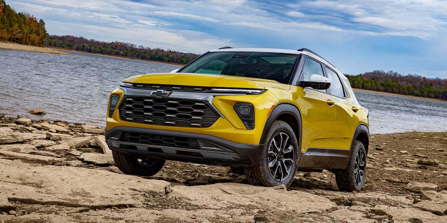 A yellow 2025 Chevrolet Trailblazer driving along rocks next to a river A yellow 2025 Chevrolet Trailblazer driving along rocks next to a river