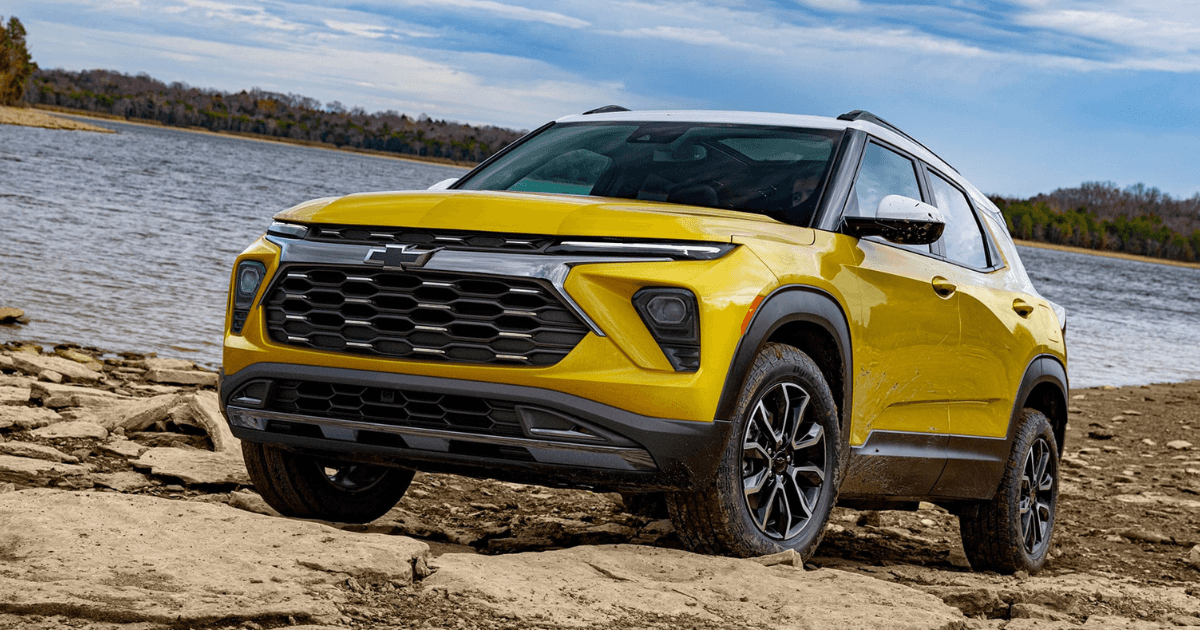 A yellow Chevrolet Trailblazer with a white roof parked on a rocky lake bed