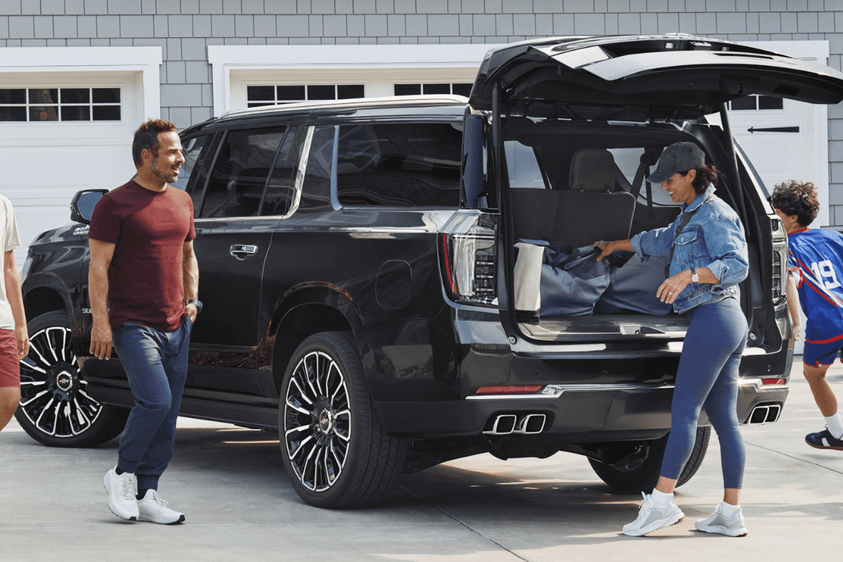 A black Chevrolet Suburban being loaded up by a family of five