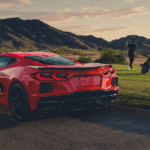 A red Chevrolet Corvette Stingray parked on the road by a golf course