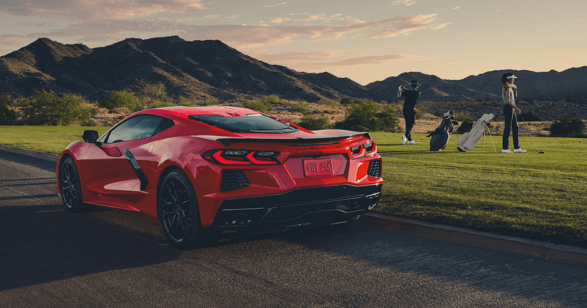 A red Chevrolet Corvette Stingray parked on the road by a golf course