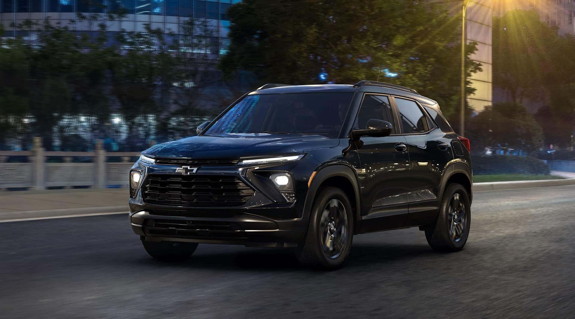 A black Chevy Trailblazer driving through a city at night
