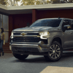 A grey Chevrolet Silverado 1500 parked in a driveway as a couple approaches it