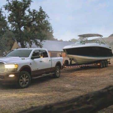 White 2020 Ram 2500 towing a boat through a large yard
