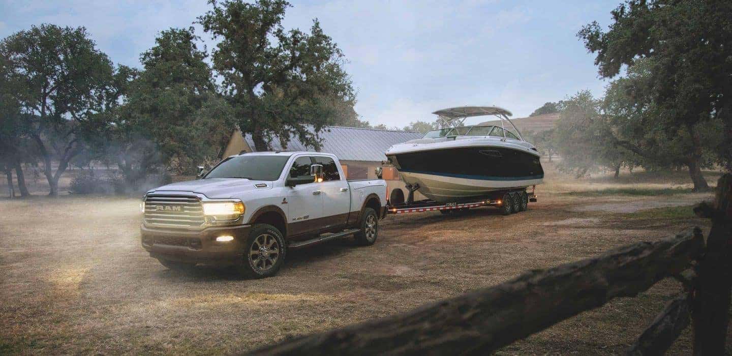 White 2020 Ram 2500 towing a boat through a large yard