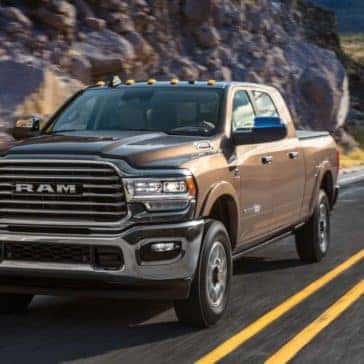 Brown 2020 Ram 2500 driving down a paved mountain-side road