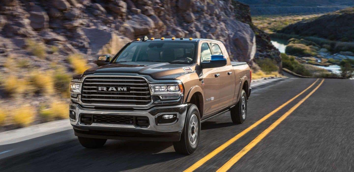 Brown 2020 Ram 2500 driving down a paved mountain-side road