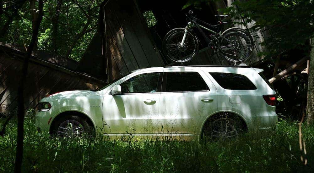 A white 2022 Dodge Durango is shown from the side parked near a remote cabin.