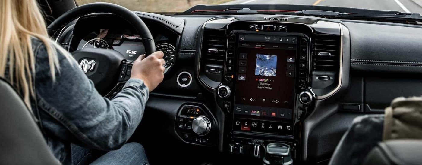 The black interior of a 2022 Ram 1500 shows the steering wheel and infotainment screen.