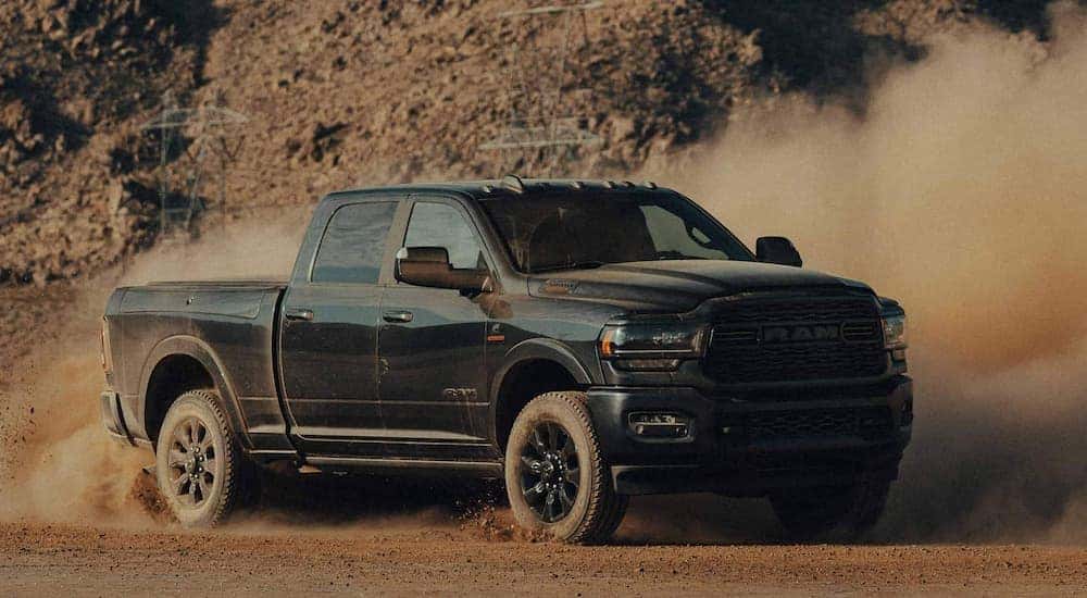 A red 2022 Ram 2500 Big Horn Night Edition is shown driving on a remote dirt trail.