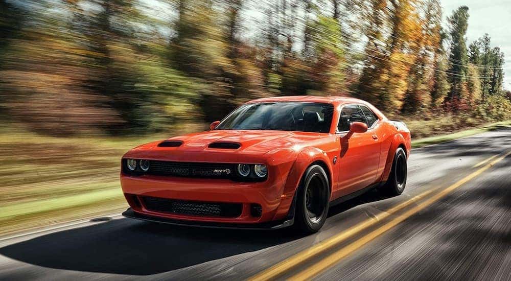 An orange 2022 Dodge Challenger Hellcat is shown from the front at an angle after the owner wondered 'should I sell my car'.