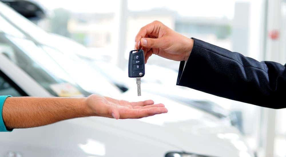 Keys are shown exchanging hands at a dealership.