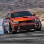 An orange 2022 Dodge Charger Scat Pack Widebody is shown from the front while drifting.