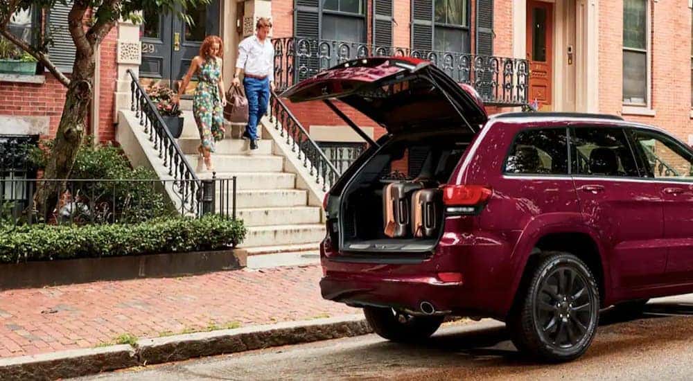 A red 2022 Jeep Grand Cherokee WK is shown on the side of a street with the lift gate open.
