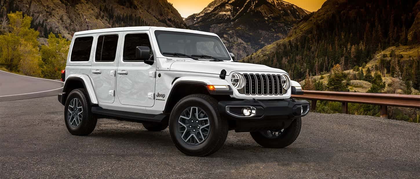 A white Jeep Wrangler parked off the side of the road in a mountainous region